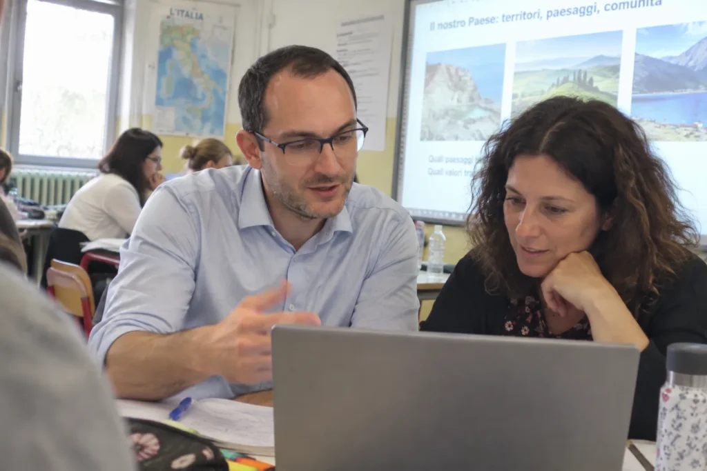 Andrea Lauricella affianca una docente al portatile durante un laboratorio di creatività digitale e intelligenza artificiale a scuola